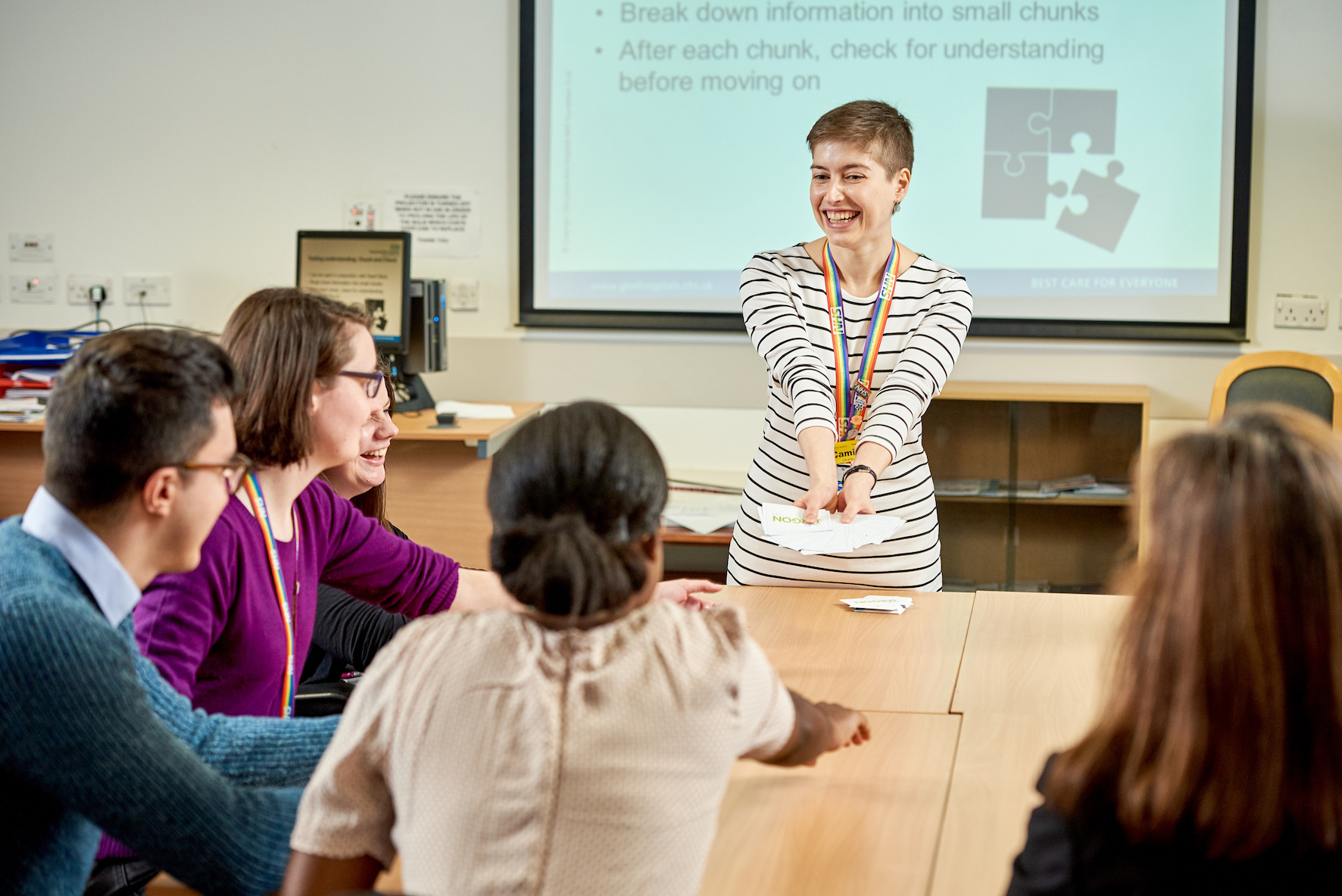 An image of a female librarian presenting cards to 5 people sat around a table.