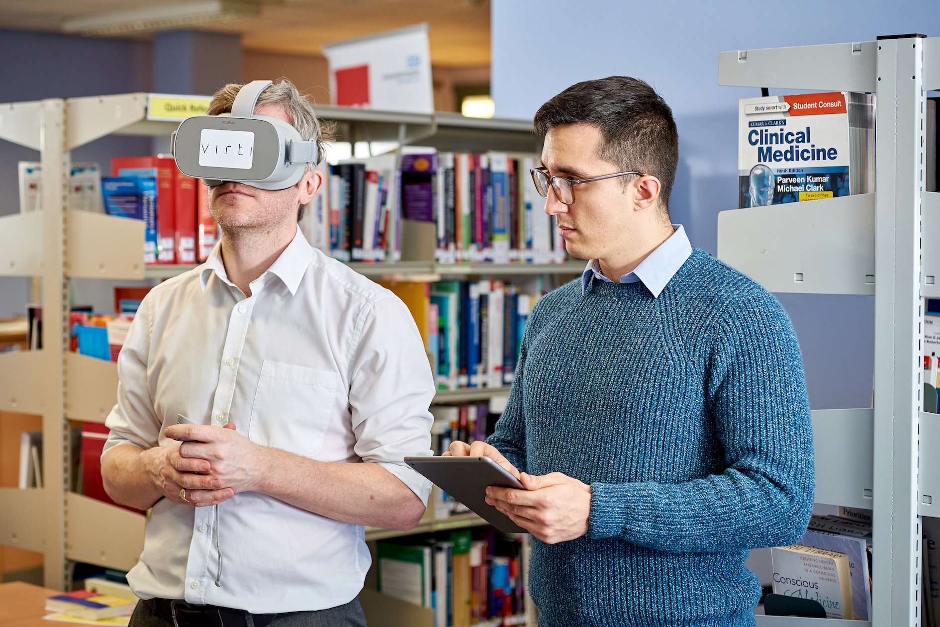 Two people standing next to each other with one of them wearing a virtual reality headset