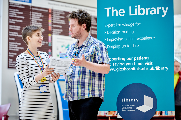 Two NHS colleagues in discussion in a hospital corridor